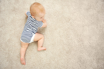 Adorable little baby crawling on light carpet