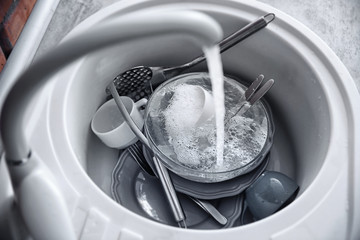 Dirty tableware in white sink at kitchen