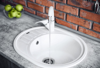 Water flowing from tap into sink at kitchen