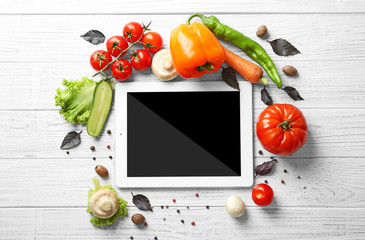 Fresh vegetables and tablet on wooden background, top view
