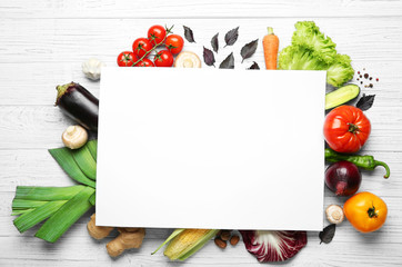 Fresh vegetables and sheet of paper on wooden background, top view