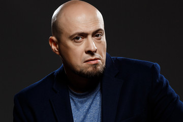 Obraz premium Close up portrait of handsome confident middle-aged businessman over black background.