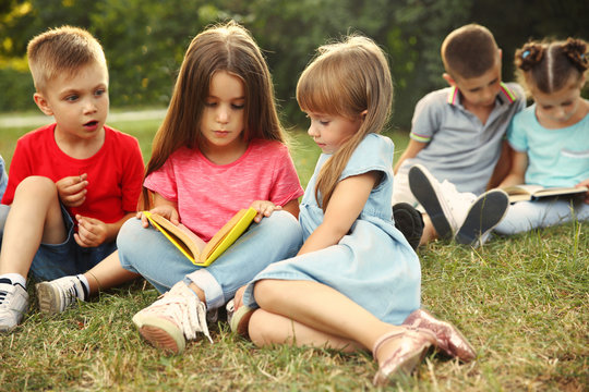 Group of happy kids reading books in park