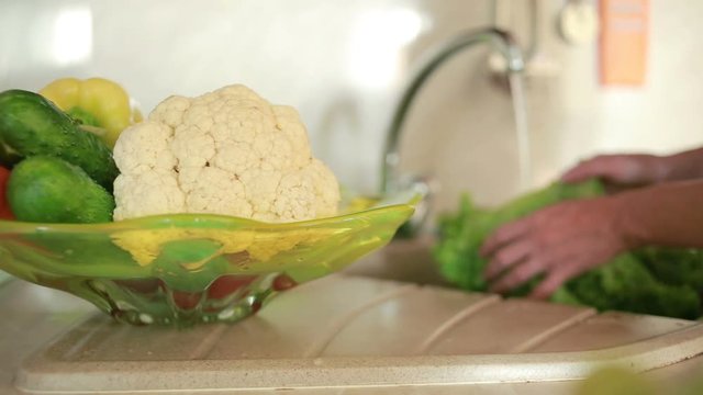 Housewife cleans a green salad in water. woman washing vegetables