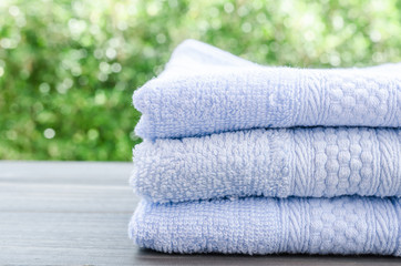 Close up of bath towels on wooden table with light bokeh backgro
