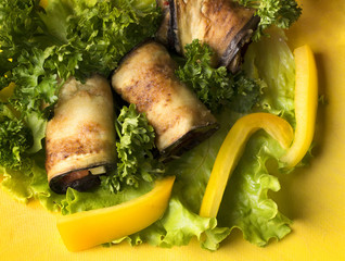 photo of fried eggplant as a cold appetizer with sweet pepper on a salad leaf with parsley on the board