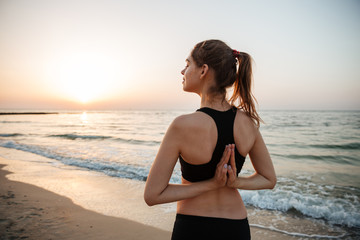 Fototapeta na wymiar Beautiful young woman stretching during yoga on the beach