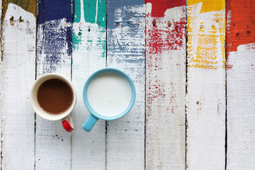 coffee and milk on grunge colorful wooden panels as background.