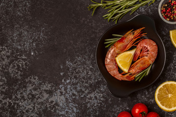 Grilled shrimps with lemon and rosemary on frying pan.