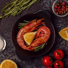 Grilled shrimps with lemon and rosemary on frying pan.