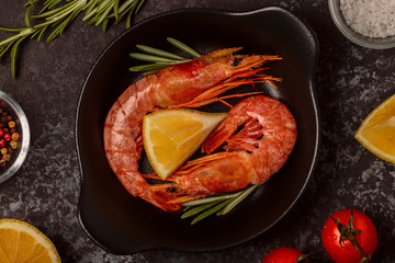 Grilled shrimps with lemon and rosemary on frying pan.