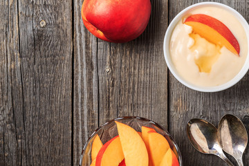 Homemade yogurt with fresh peaches on a wooden background.
