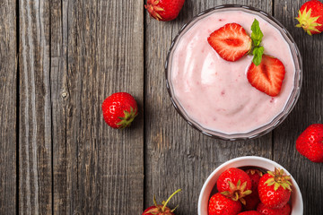 Homemade yogurt with fresh strawberry on a wooden background.