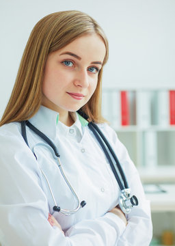 Portrait of a confident female doctor sitting on the office background and looking at the camera.