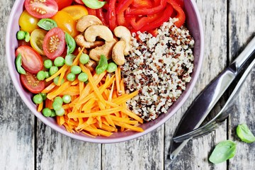 Quinoa bowl with raw vegetables and nuts. Superfoods and clean eating concept. Selective focus
