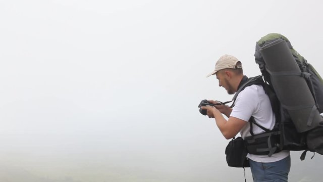 Tourist with backpack takes photos on peak of rock