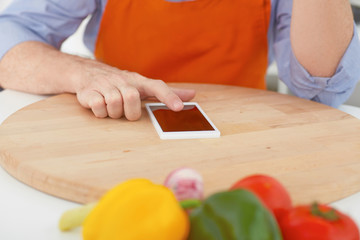 Closeup of man pointing finger to smartphone. Cooking, technology and home concept.