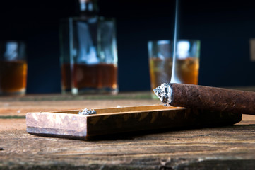 Cigar and whisky with ice on wooden table