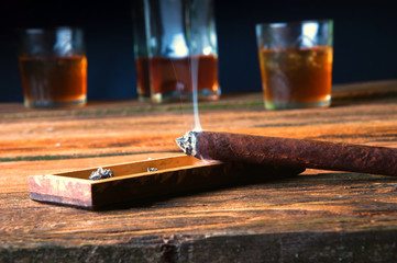 Cigar and whisky with ice on wooden table
