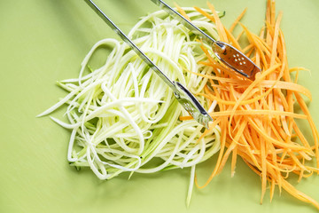 Zucchini and carrot spirals on green chopping board