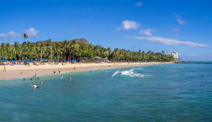 Fototapeta na wymiar Sun lovers on Waikiki beach in Honolulu, Usa. Waikiki beach is neighborhood of Honolulu, best known for white sand and surfing.