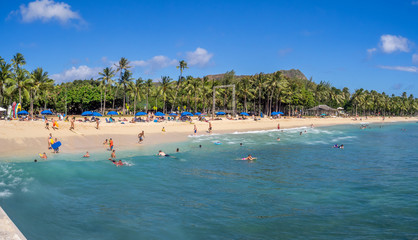 Sun lovers on Waikiki beach in Honolulu, Usa. Waikiki beach is neighborhood of Honolulu, best known for white sand and surfing.