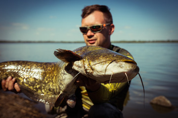 Happy angler with catfish fishing trophy 