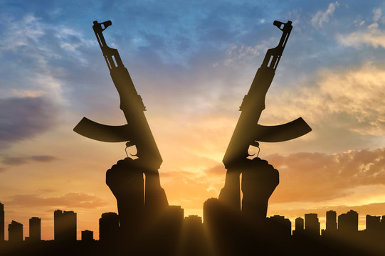 Silhouette of men hands holding rifle during sunset