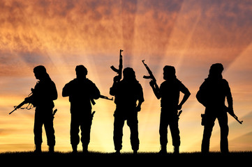 Fototapeta na wymiar Silhouette of men with rifles standing against cloudy sky during sunset