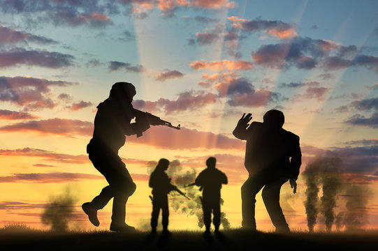 Silhouette of armed man attacking civilian against cloudy sky during sunset