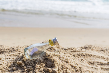 SOS message in glass bottle on the beach.