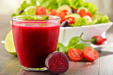 Composition with glass of juice and vegetable salad bowl.