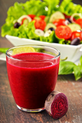 Composition with glass of juice and vegetable salad bowl.
