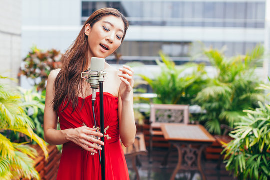 Asian woman singing on the rooftop of the building in outdoor scene
