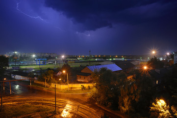 Fototapeta na wymiar Black cloud and lightning at night over railway cargo yard
