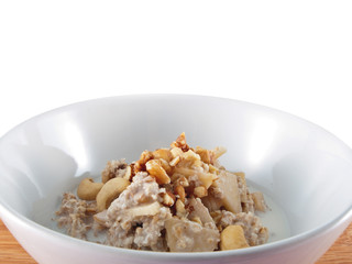 a bowl of oatflakes in soy milk with apple slices and nuts