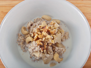 a bowl of oatflakes in soy milk with apple slices and nuts