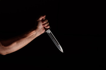 Man's hand with a knife in the dark
