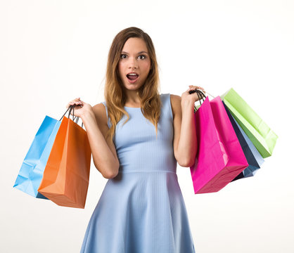 Young woman in a blue dress with colorful shopping bags.