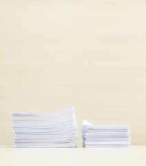 Closeup pile of work paper on blurred wooden desk and wall textured background in the meeting room under window light , hard work concept with copy space