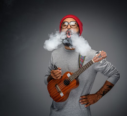 Male holding acoustic small guitar and smoking a cigarette.