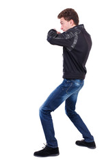 Naklejka premium back view of guy funny fights waving his arms and legs. Isolated over white background. Rear view people collection. backside view of person. Curly guy in a black leather jacket fights waving his