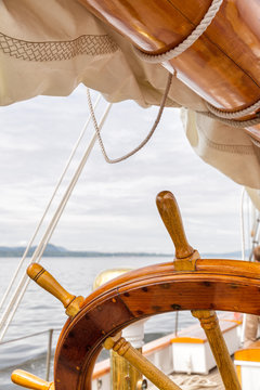 Wooden wheel on a big sailboat at sea. Close up nautical detail