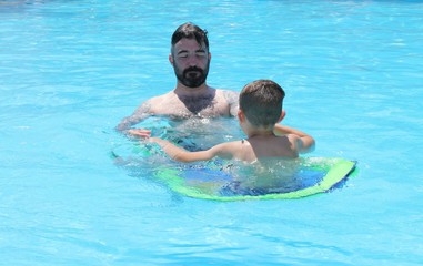 A father with his young son in a swimming pool while on vacation, 2016 