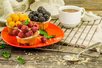 beautiful cupcakes with berries on wooden background in red plate