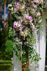 Wedding arch decorated with flowers and glass hanging vases