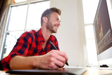 Handsome middle age man at desk with stylus and desktop