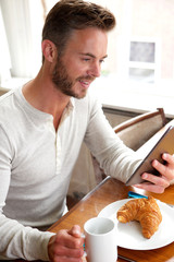 Happy older man looking at tablet over breakfast