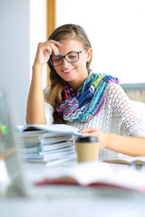 Young woman sitting at a desk among books