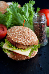 Hamburger with salad, tomato, meat on black  backdrop